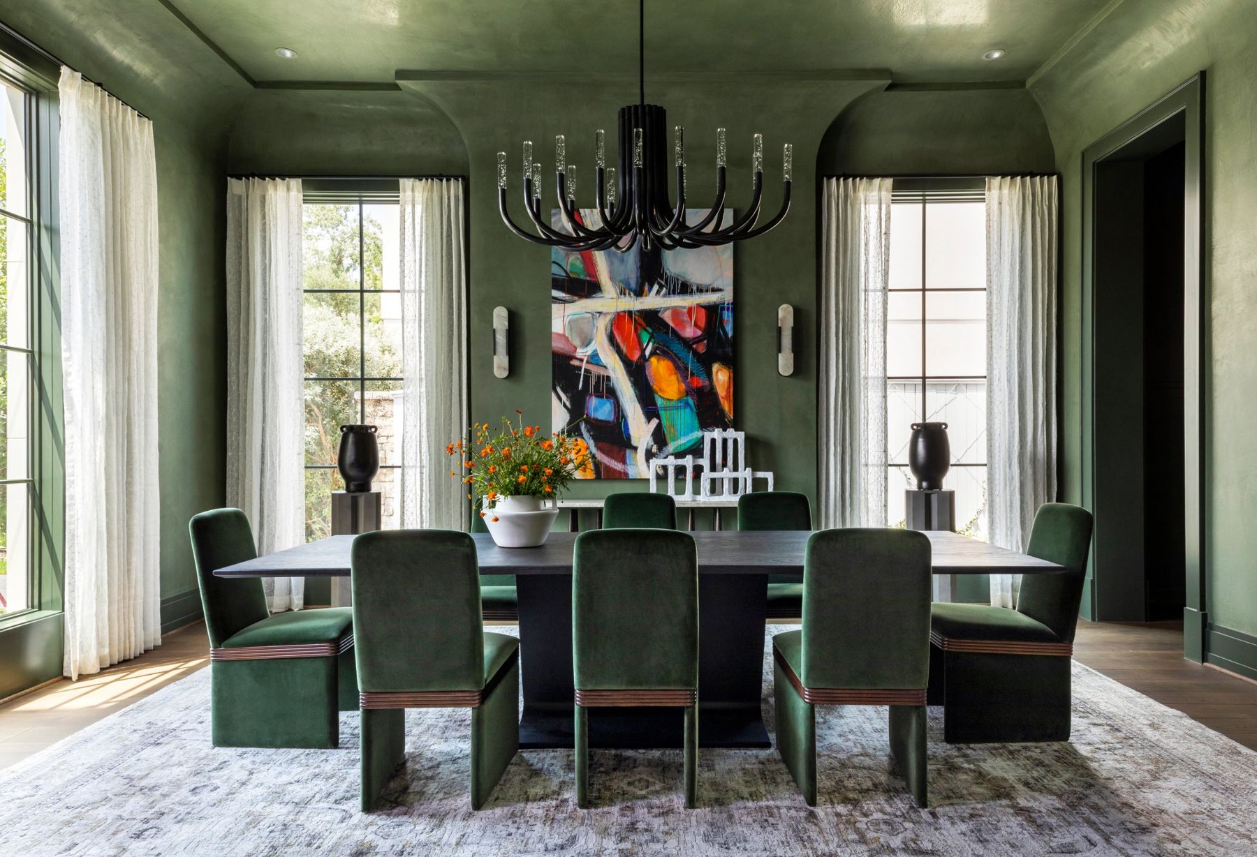Green plaster dining room with a sculptural chandelier and alabaster sconces