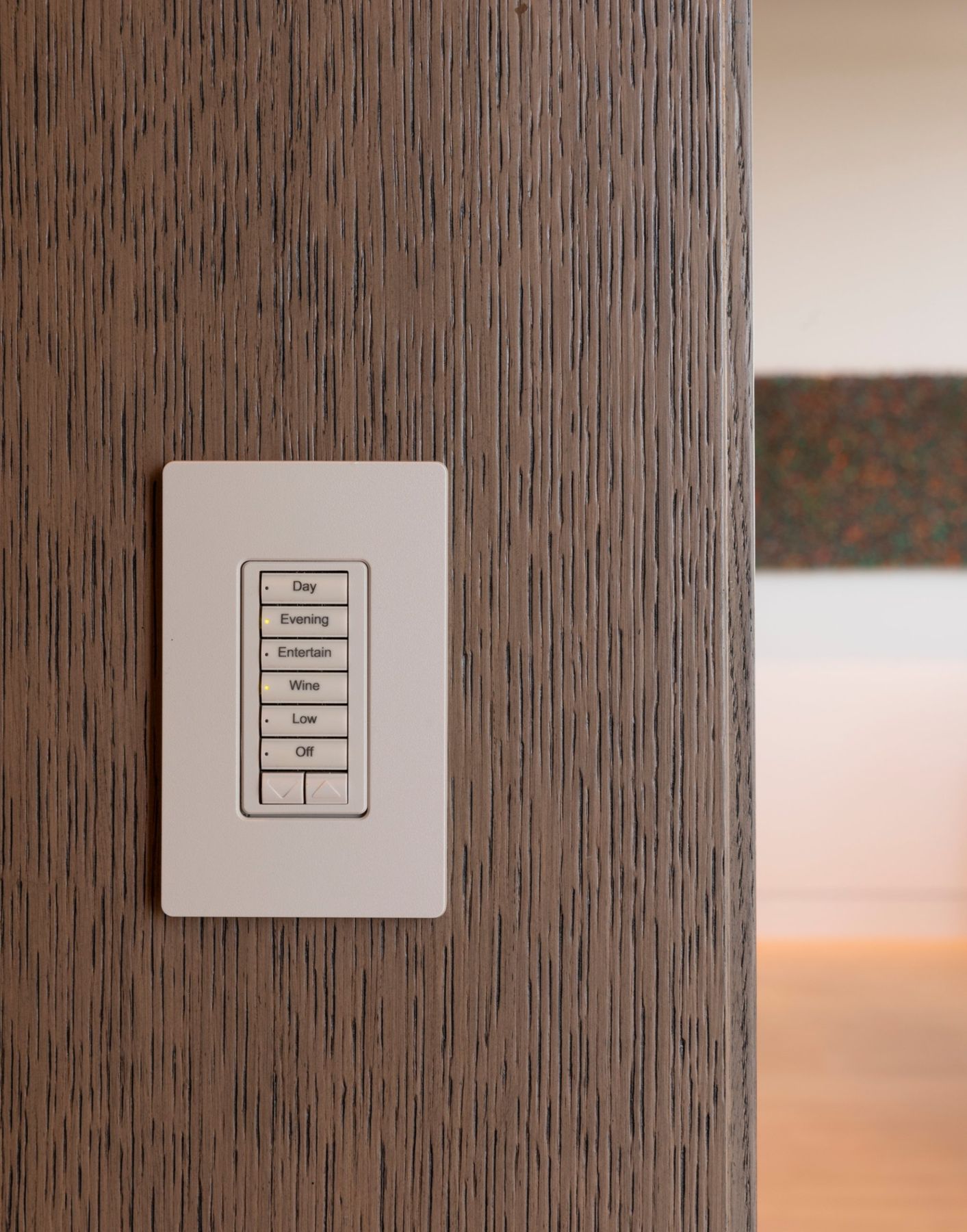 Lutron keypad on an oak-paneled wall with buttons for Day, Evening, Entertain, Wine, Low and Off
