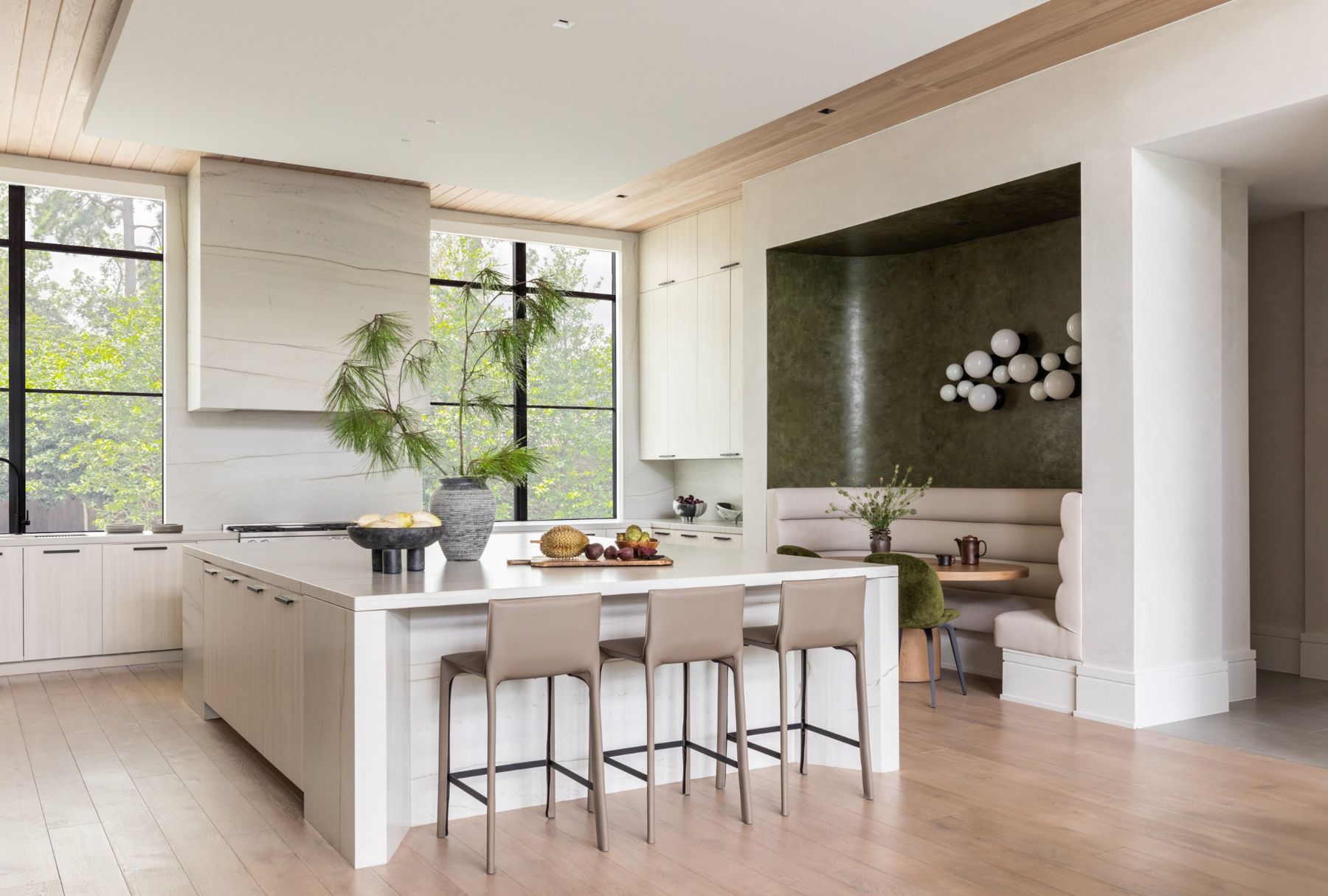 Light oak kitchen with a stone waterfall island and a green plaster breakfast nook